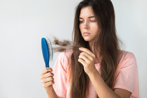 A queda de cabelo ocorre toda vez que manuseamos os fios, seja na hora da lavagem, quando penteamos ou passamos a mão. Por isso, quando a queda é composta por uma grande quantidade de fios, deve-se averiguar a causa, já que ela pode estar relacionada a um desequilíbrio hormonal do organismo. Os cabelos possuem um forte apelo estético. Apesar de terem apenas a função de proteger o couro cabeludo da incidência solar, eles emolduram o rosto e estão associados à vitalidade, beleza e saúde. O ser humano perde, por dia, uma média de 150 fios de cabelo. Entenda quando a queda de cabelo é resultado de problemas hormonais, a seguir. O que pode provocar a queda de cabelo? Vários podem provocar a queda de cabelo. Entre eles estão a anemia, estresse, excesso de vitaminas, gravidez, uso de medicamentos, maus hábitos, fatores emocionais e desequilíbrio hormonal. Para evitar que o problema se torne crônico, levando a um quadro de alopecia, deve-se procurar um médico especialista, para investigação da causa e tratamento. Quando a queda de cabelo é derivada de um problema no sistema endócrino, alguns hormônios podem ser os causadores. Descubra, a seguir. Queda de cabelo por desequilíbrio hormonal Alterações nos hormônios T3 e T4 Problemas na tireoide, como hipotireoidismo e hipertireoidismo, podem causar a queda de cabelo. A tireoide é uma glândula localizada na região do pescoço. Sua principal função é produzir os hormônios tiroxina (T4) e  triiodotironina (T3). Quando essas substâncias estão em quantidades alteradas no organismo, elas causam diversos desequilíbrios. E, consequentemente, podem prejudicar a produção dos fios de cabelo. Por afetar diretamente a vitalidade, essas alterações prejudicam os fios. Com isso, eles se tornam finos, fracos, secos, opacos, descoloridos e com maior tendência à quebra e queda. Cortisol Conhecido como o hormônio do estresse, o cortisol é importante porque atua no controle do estresse. Outras funções da substância são a redução de inflamações e a manutenção dos níveis de açúcar no sangue, contribuindo, também, para o sistema imunológico. Além do uso de medicamentos, níveis altos de cortisol podem ser provocados quando um indivíduo passa por um constante período de estresse. Isso acontece porque em pessoas que sofrem de estresse crônico, sua produção é contínua. Logo, dentre os sintomas do excesso de cortisol está a queda acentuada de cabelo, por exemplo.  Testosterona A testosterona é o hormônio que pode provocar a queda de cabelo mais temida por homens e mulheres. Este hormônio é um dos responsáveis por causar a calvície. A alopecia androgenética provocada pela testosterona afeta 50% dos homens aos 50 anos e 40% das mulheres após a menopausa. A queda dos cabelos ocorre porque o DTH, substância derivada da testosterona, interage, de forma excessiva, com os receptores de andrógenos presentes nos folículos pilosos. Essa interação provoca a atrofia dos bulbos capilares. Consequentemente, deixa os cabelos mais finos e acelerando a queda definitiva. Controle do desequilíbrio hormonal e da queda de cabelo O desequilíbrio hormonal pode provocar muito mais do que a queda de cabelo: essa situação é um sério fator de risco para inúmeras doenças. Diante disso, observe e conheça o seu corpo e, a qualquer sinal de alteração, procure um médico. Assim como outras disfunções, os problemas hormonais, quanto antes descobertos, mais fáceis serão tratados. Quer saber mais? Clique no banner e saiba mais sobre Medicina Integrativa.